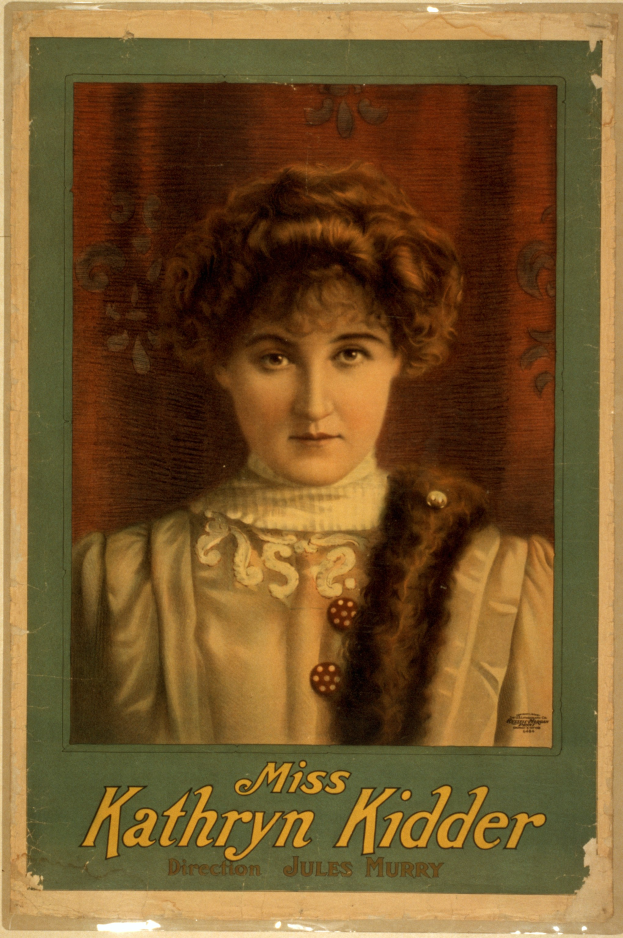 Ein altes Foto einer Frau mit warmem Lächeln, die ein weißes Kleid und ein gemustertes Tuch trägt, ihr Haar ist zu einem Dutt gebunden und sie schaut direkt in die Kamera mit dem Text "Miss Kathryn Kidder" unten.