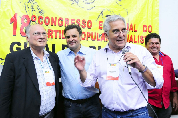 Ein Mann spricht in ein Mikrofon vor einem gelben Vorhang mit der Aufschrift "18-Grad-Kongress O".