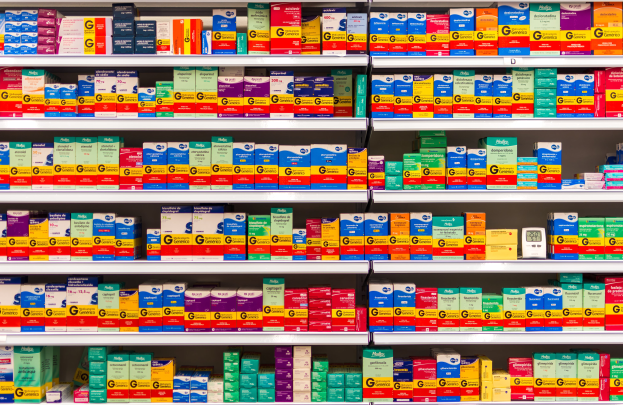 Ein Apothekeregal mit verschiedenen Medikamenten, Schachteln und anderen Gegenständen, die ordentlich auf den Regalen angeordnet sind.