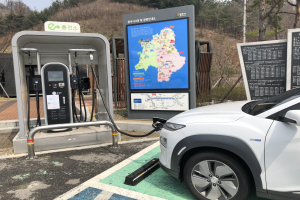 Laden eines Elektroautos an einer Station in Seoul, Südkorea, umgeben von Bäumen mit dem Himmel im Hintergrund.