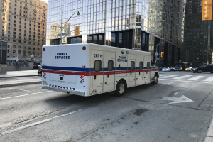 Ambulanz auf einer städtischen Straße mit hohen Gebäuden, Straßeninfrastruktur und Passanten geparkt, unter einem sichtbaren Himmel.