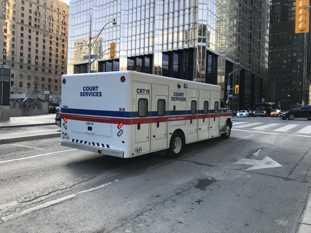 Ambulanz auf einer städtischen Straße mit hohen Gebäuden, Straßeninfrastruktur und Passanten geparkt, unter einem sichtbaren Himmel.