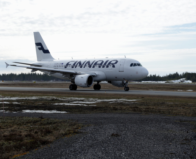 Finnair Airbus A320-200 auf der Rollbahn am Seattle-Tacoma International Airport mit grüner Wiese, Bäumen und einem klaren blauen Himmel im Hintergrund.