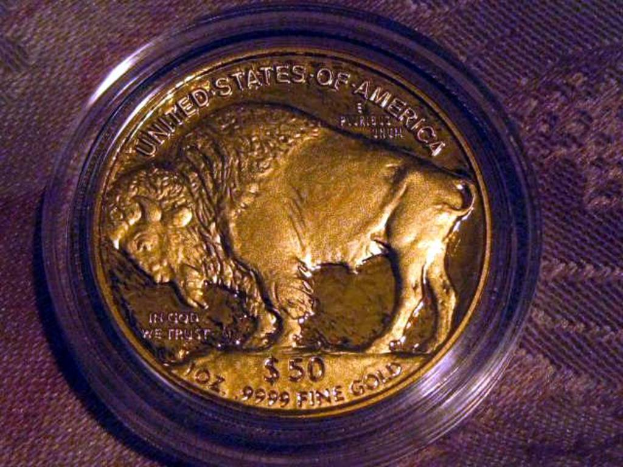 Eine gold- und braune Münze mit der Aufschrift 'The United States Of America' auf einem braunen Teppichboden.