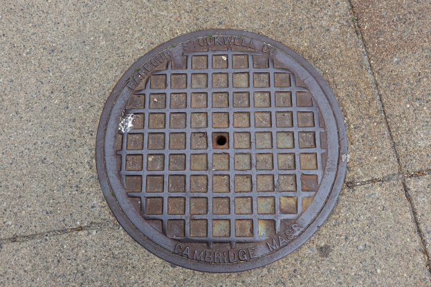 Ein rundes Metallgulldeckel auf einem Stadtweg mit eingravierter Text.