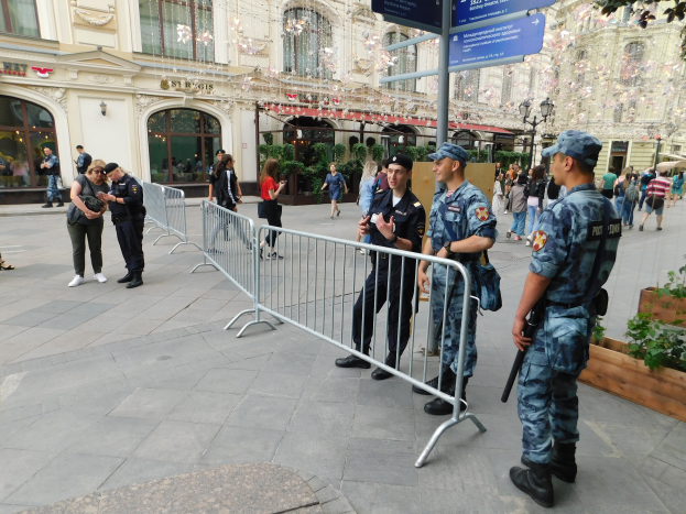 Eine Gruppe von Polizisten steht vor einer Menge, einige halten Waffen, mit Absperrungen und Schildern im Vordergrund und Gebäuden, Laternen, Pflanzen und Bäumen im Hintergrund in Wien, Österreich während einer Anti-Terror-Operation.