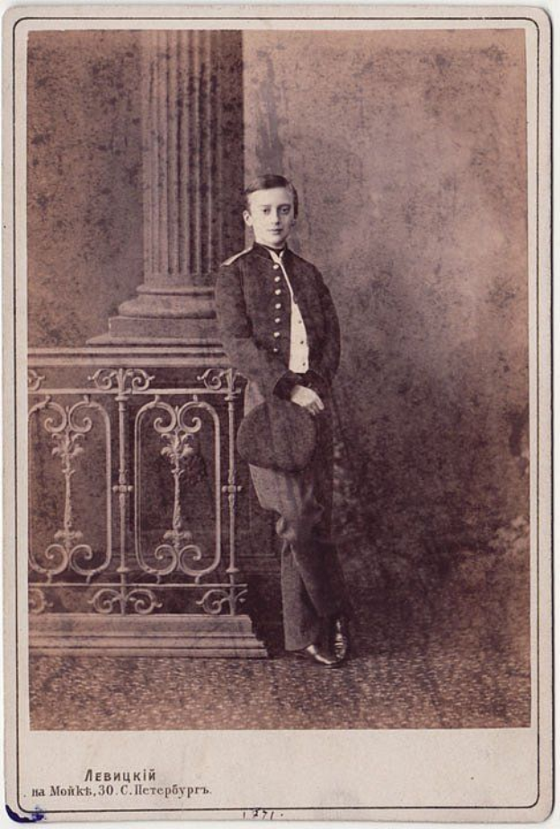 Ein altes Schwarz-Wei√ü-Foto eines Mannes in Uniform, der vor einem Gel√§nder mit einer S√§ule im Hintergrund steht, mit einem Text am unteren Rand, der lautet: "Левикий на мольки 30 в с шерерухри из компьютерный".