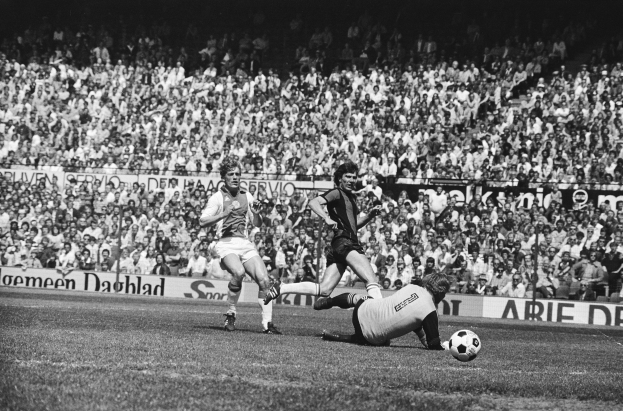 Schwarzes und weißes Foto von Männern, die auf einem Feld Fußball spielen, mit Zuschauern im Hintergrund und einer Banner mit der Aufschrift "Bundesliga 1978-79 Ajax 1-1 Hannover 96."