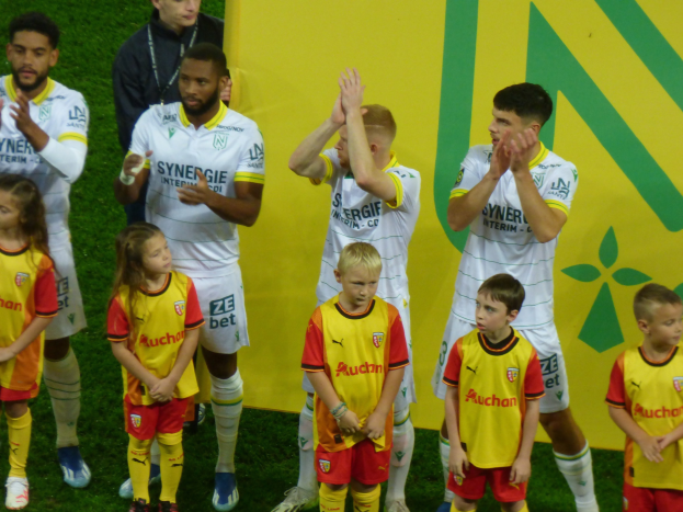 Eine Gruppe von Fußballspielern in Uniform, die auf einem Ligue-1-Feld jubeln.