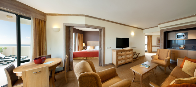Ein Wohnzimmer mit einem Fernseher, Sofa, Stühlen, Kissen, einer Mikrowelle, einem Bett und einem Tisch.