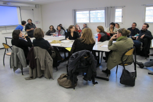 Eine Gruppe von Menschen, die sich unterhalten, wobei zwei andere getrennt stehen und sprechen.