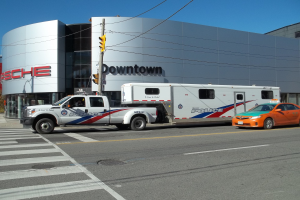 Polizeifahrzeug vor einem Gebäude mit Text geparkt, mit einer Ampel und Kabeln im Vordergrund, Bäumen und einem klaren blauen Himmel im Hintergrund.