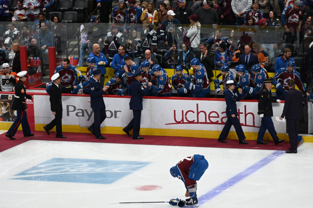 Ein Eishockeyspiel in einer großen Arena mit Zuschauern, ein Auto im Vordergrund, Banner und Deckenbeleuchtung und Bildschirm.