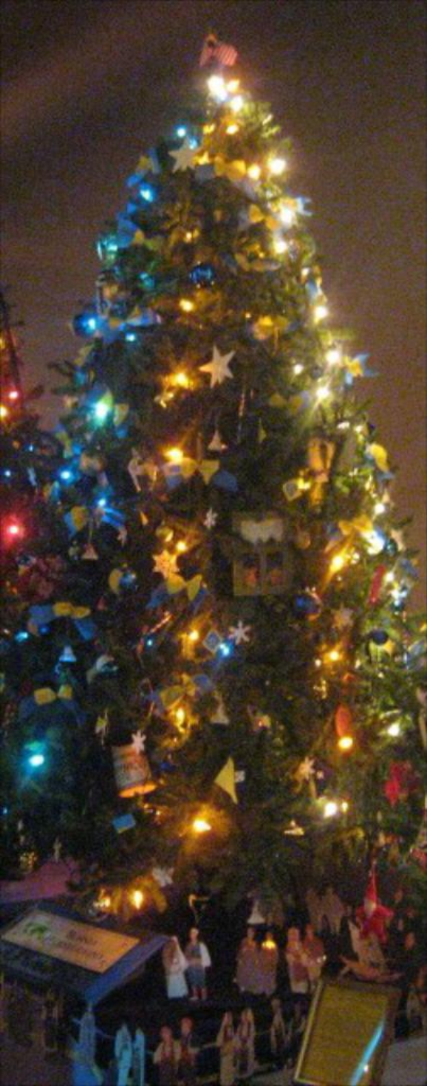 Ein geschmückter Weihnachtsbaum mit Statuen von Menschen, die auf einem Tisch darunter platziert sind.