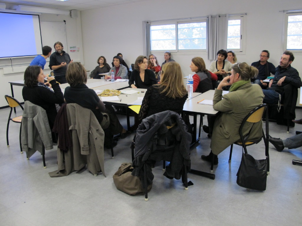 Eine Gruppe von Menschen, die sich unterhalten, mit zwei Personen im Hintergrund, die sich unterhalten.