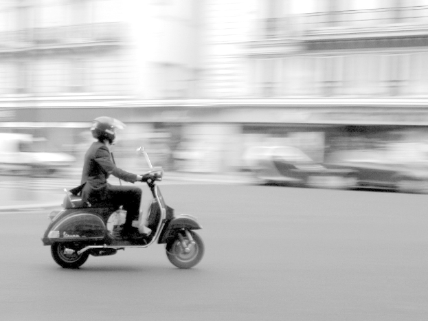 Eine Person, die ein Roller auf einer Stra├če fahrt.