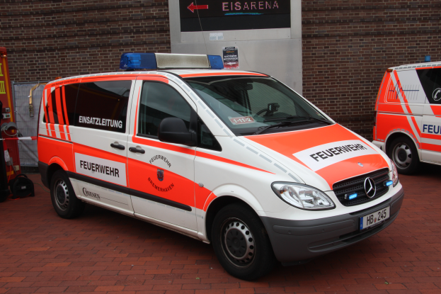 Zwei Rettungswagen nebeneinander vor einem Gebäude geparkt, mit einem Feuerlöscher und anderen Gegenständen auf der linken Seite.