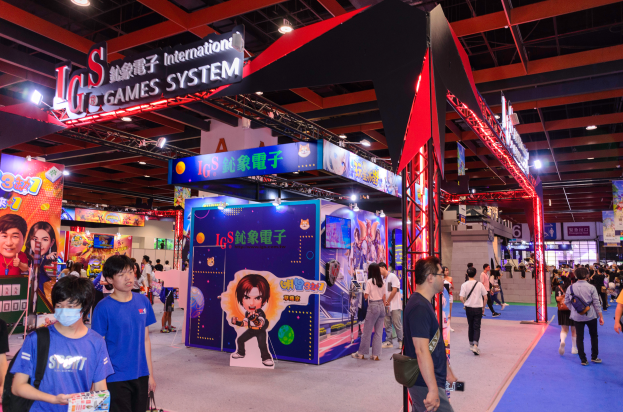 Eine Gruppe von Menschen geht durch einen Messesaal mit Ständen, trägt Taschen und hält Gegenstände, mit vielen anderen im Hintergrund auf einer Spielemesse in China.