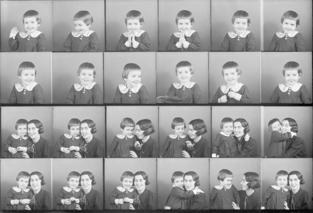 Schwarz-weißes Foto einer Gruppe von Kindern mit einer Frau in der Mitte, die ein Baby hält und beide warmherzige Ausdrücke zeigen.