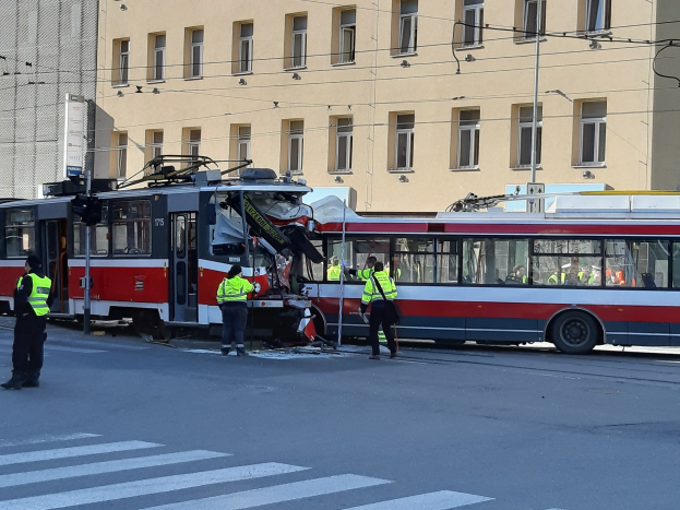 Rote und weiße Straßenbahn krachte auf die Seite der Straße mit ein paar Menschen in der Nähe und einem Gebäude im Hintergrund.