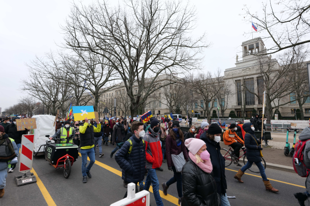 Eine große Gruppe von Menschen marschiert auf einer Straße in Washington, D.C. am 21. Januar 2020, einige halten Schilder und Banner, andere fahren Fahrräder, mit Schildern, Bäumen und einem klaren blauen Himmel im Hintergrund.