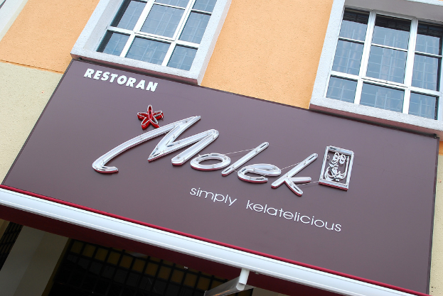 Ein Gebäude mit Fenstern und einer Werbetafel, auf der "Molek" steht.