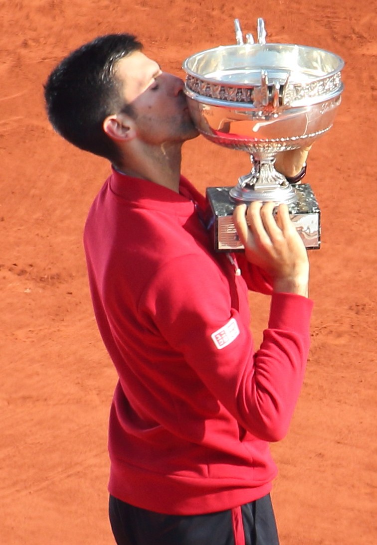 Novak Djokovic hält den French-Open-Pokal nach Sieg über Rafael Nadal in der Herren-Einzel-Finalrunde, feiert triumphierend und küsst den Pokal.