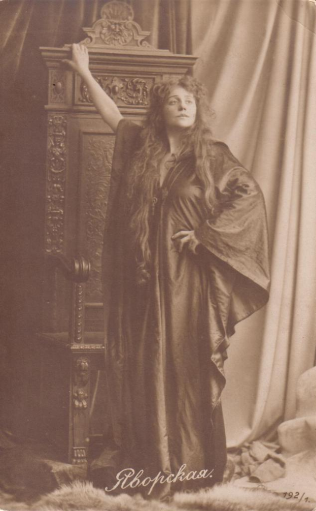 Ein Schwarz-Weiß-Foto einer Frau in einem Kleid, die vor einem Schrank mit einem Vorhang im Hintergrund steht, mit Text unten, der 'Gustav Klimt, russische Schauspielerin und Sängerin' lautet.