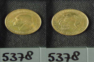 Zwei Goldmünzen aus Deutschland im Jahr 1922, jeweils mit einem Nennwert von 100 Mark, werden auf einer schwarzen Oberfläche mit Zahlen unten plaziert.