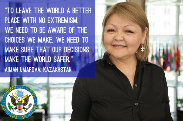 Eine Frau in einem schwarzen Kleid steht vor einem Fenster mit einer Aussage über die Weltverbesserung, mit Flaggen im Hintergrund.