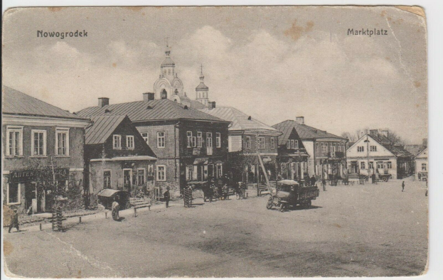 Ein altes Schwarz-Weiß-Foto einer Stadtstraße in Nowogrodeek, Deutschland, das Gebäude, Menschen, Karren, Pfähle, Bäume und den Text "Marktplatz in Nowogrodeek, Deutschland" oben und unten zeigt.