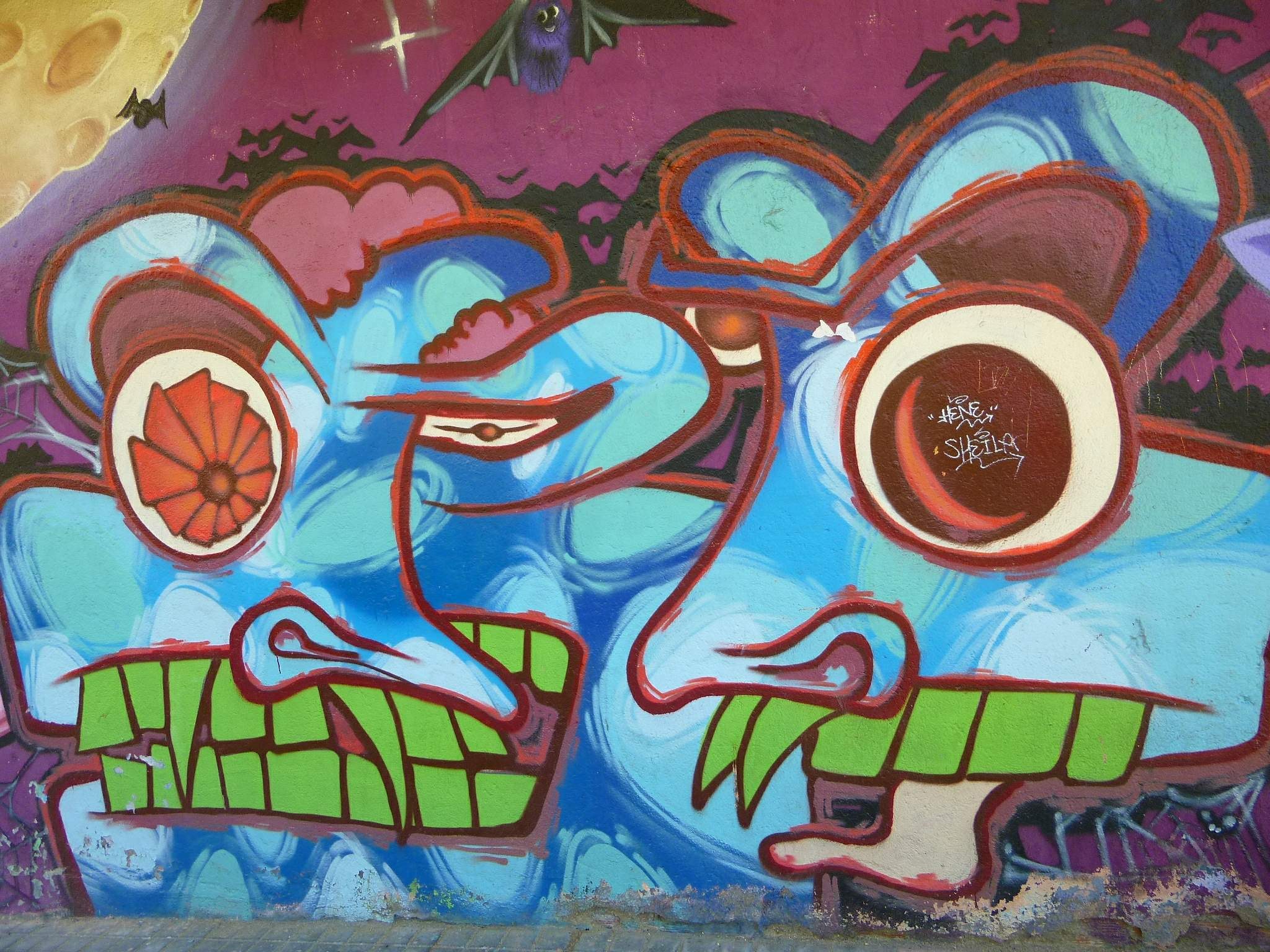 Ein farbenfrohes Wandgemälde mit buntem Graffiti-Art auf der Seite eines Gebäudes.