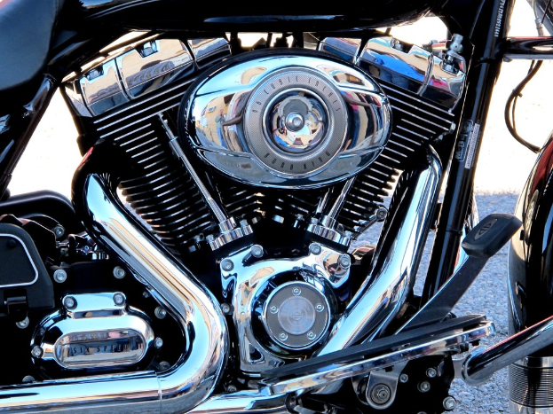 Eine Sammlung von Motorradteilen, darunter ein Motor, ein Kühler, ein Auspuffrohr, ein Gang, Stangen, Muttern und Drähte.