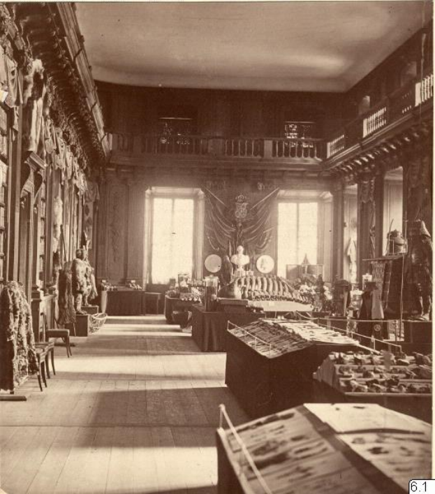 Schwarzes und weißes Foto eines Raums im Museum of Fine Arts, London, mit Tischen, Stühlen, Skulpturen an den Wänden, Fenstern mit Vorhängen und Geländern.