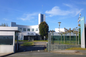Ein großes, mehrfenstriges Gebäude mit einem Tor davor, umgeben von Straßenlaternen, Lampen, Gittern, Bäumen und Gras, unter einem bewölkten Himmel, das als Hauptsitz von Iberostica in den Niederlanden dient.