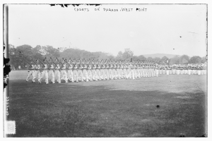 Gruppe von Menschen auf dem Boden stehend, einige halten Gewehre, Bäume, Hügel und bewölkter Himmel im Hintergrund, mit Text 'cadets on parade west point' oben.