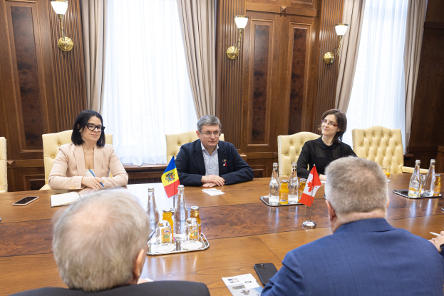 Eine Gruppe von Menschen, die um einen Holztisch in einem formellen Setting sitzen und sich mit EU-bezogenen Dokumenten und Gegenständen beschäftigen.