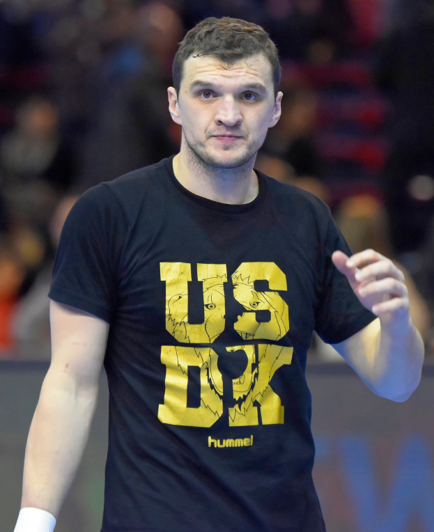Ein Mann in einem schwarzen T-Shirt und weißen Shorts steht auf einem Court, mit dem Text "Hummel USA vs Germany" unten.