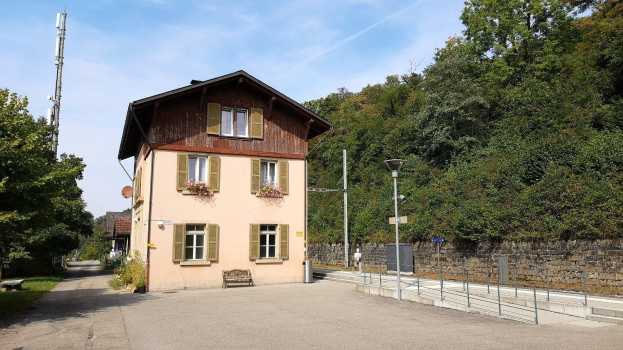 Ferienhaus zum Verkauf in Baden-Württemberg, Deutschland, mit einem Gebäude mit vielen Fenstern, einer Vorderseite, einer Straßenlaterne, Grünfläche und einem bewölkten Himmel.