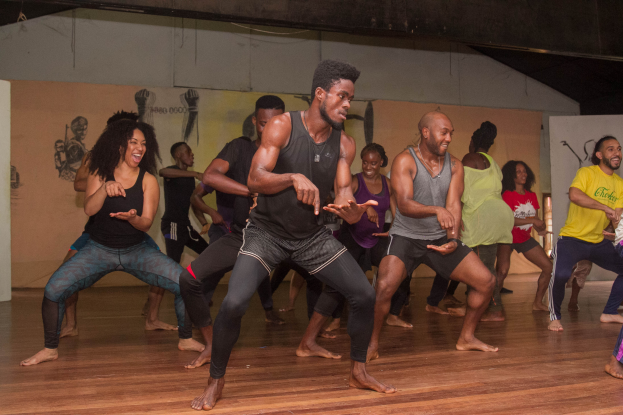 Eine Gruppe von Menschen in einem Tanzkurs an der Universität Chicago, die auf dem Boden tanzen, mit Gemälden an der Wand und einer Decke im Hintergrund.