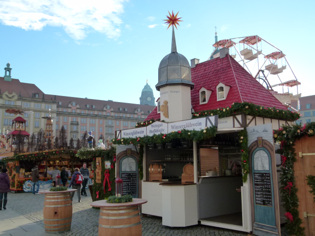Ein lebendiger Weihnachtsmarkt in Nürnberg, Deutschland, mit Menschen um dekorierte Stände, Gebäude, ein Riesenrad und einen bewölkten Himmel, mit einer Tafel auf der rechten Seite.